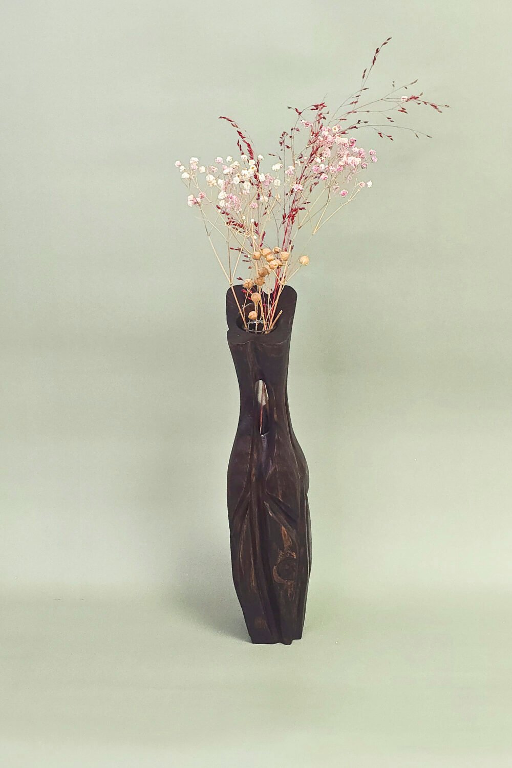 Medinė vaza su krūmo šakelėmis ant kalėdiškai padengto stalo.